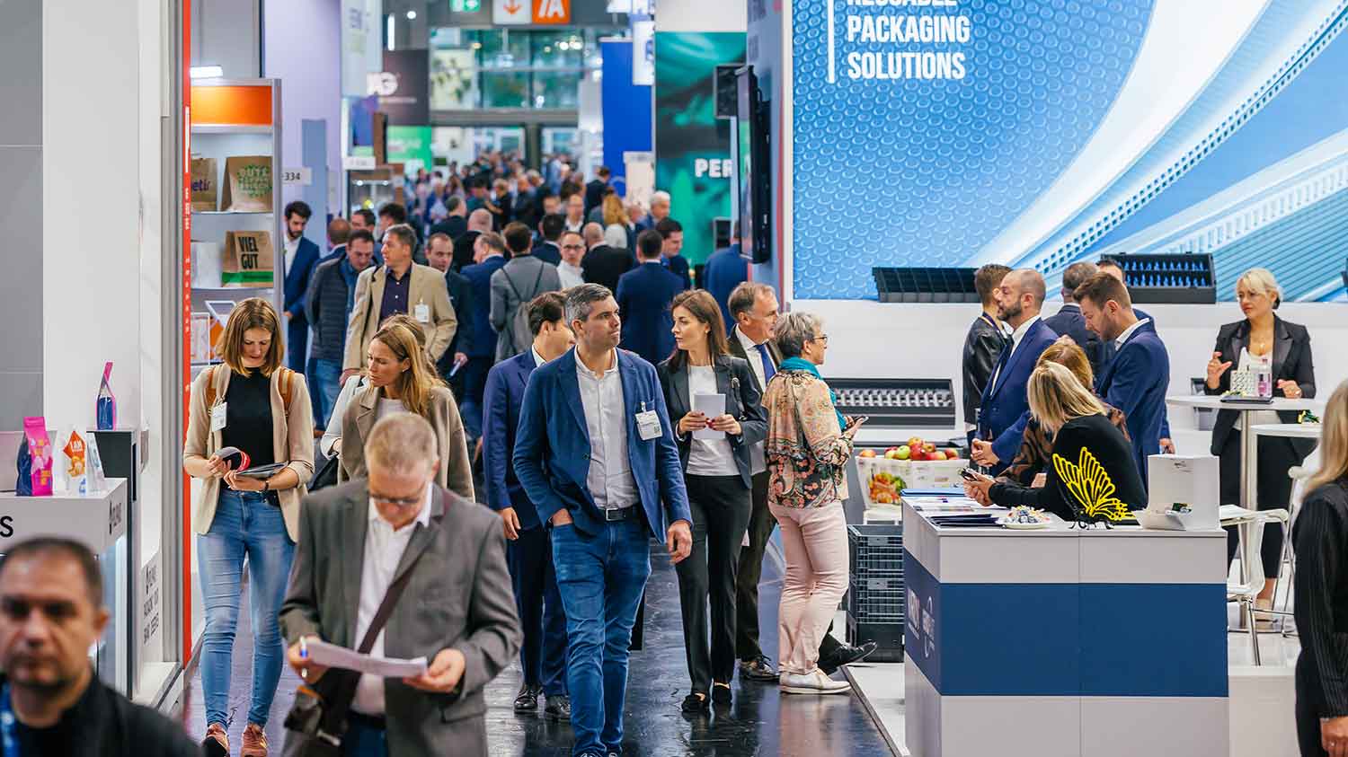 Besucher laufen über die Messe und schauen bei den Messeständen der Aussteller vorbei