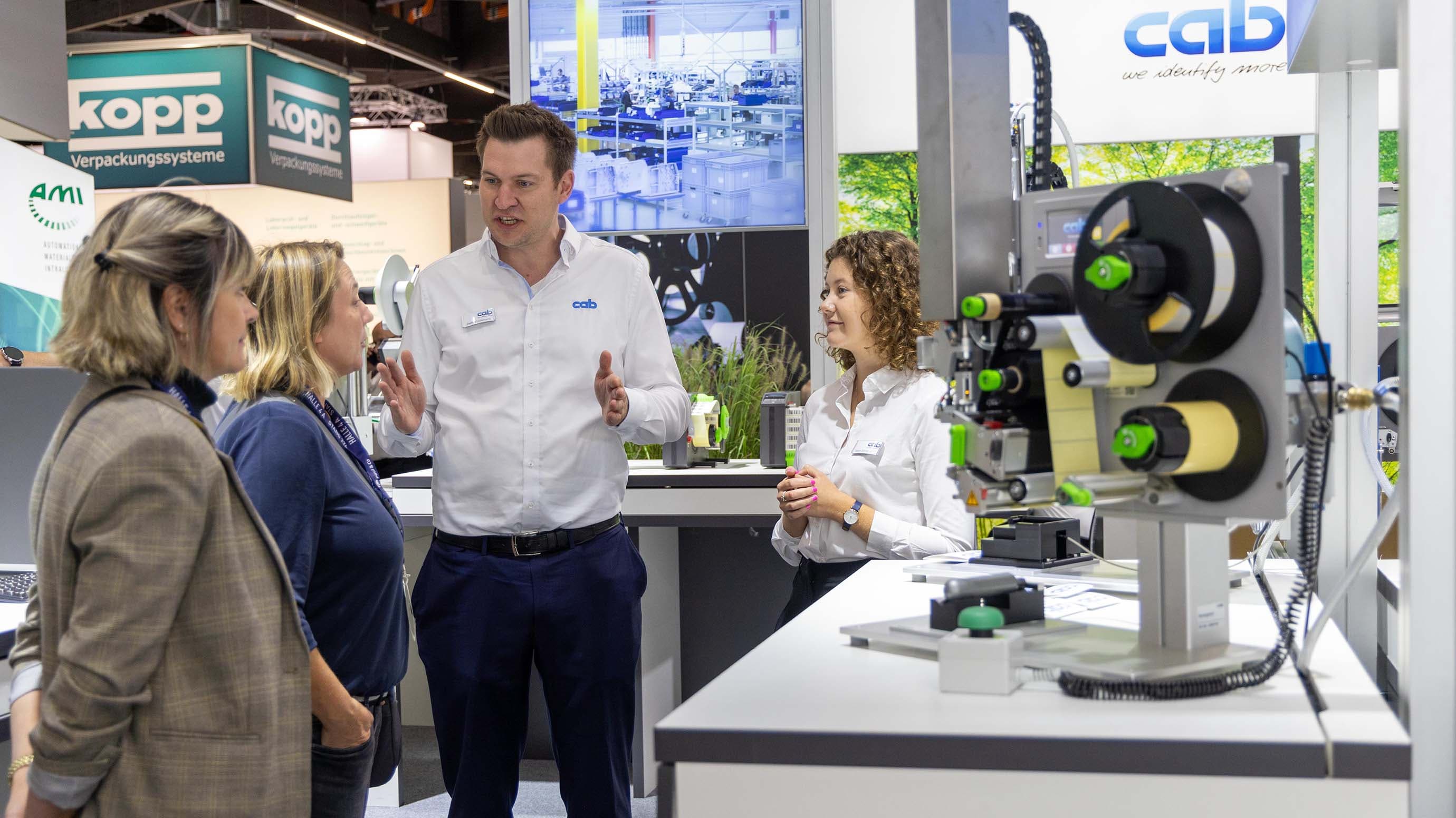 Ein Aussteller präsentiert Besuchern ein Ausstellungsstück