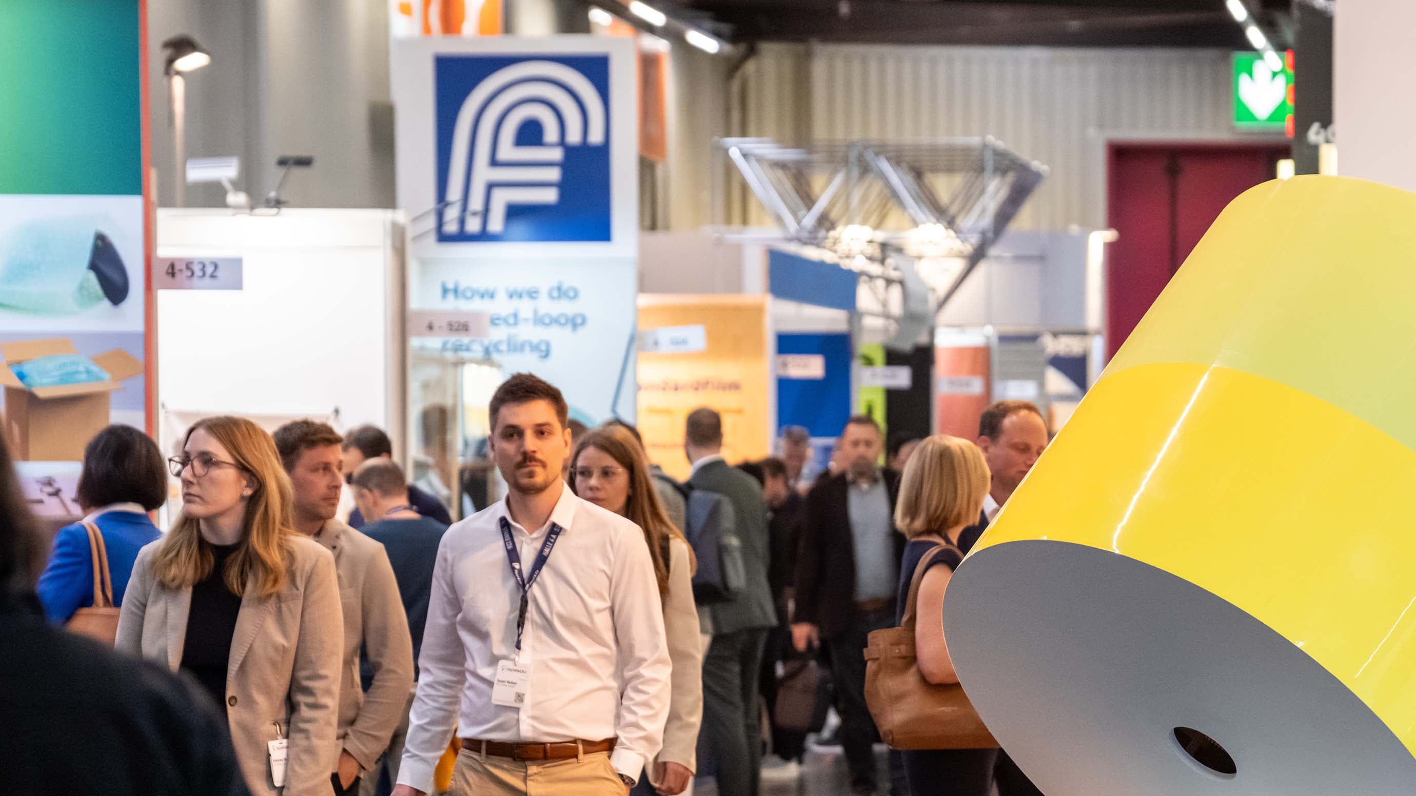 Besucher gehen über die Messe, vorbei an Stände und Ausstellungsstücke